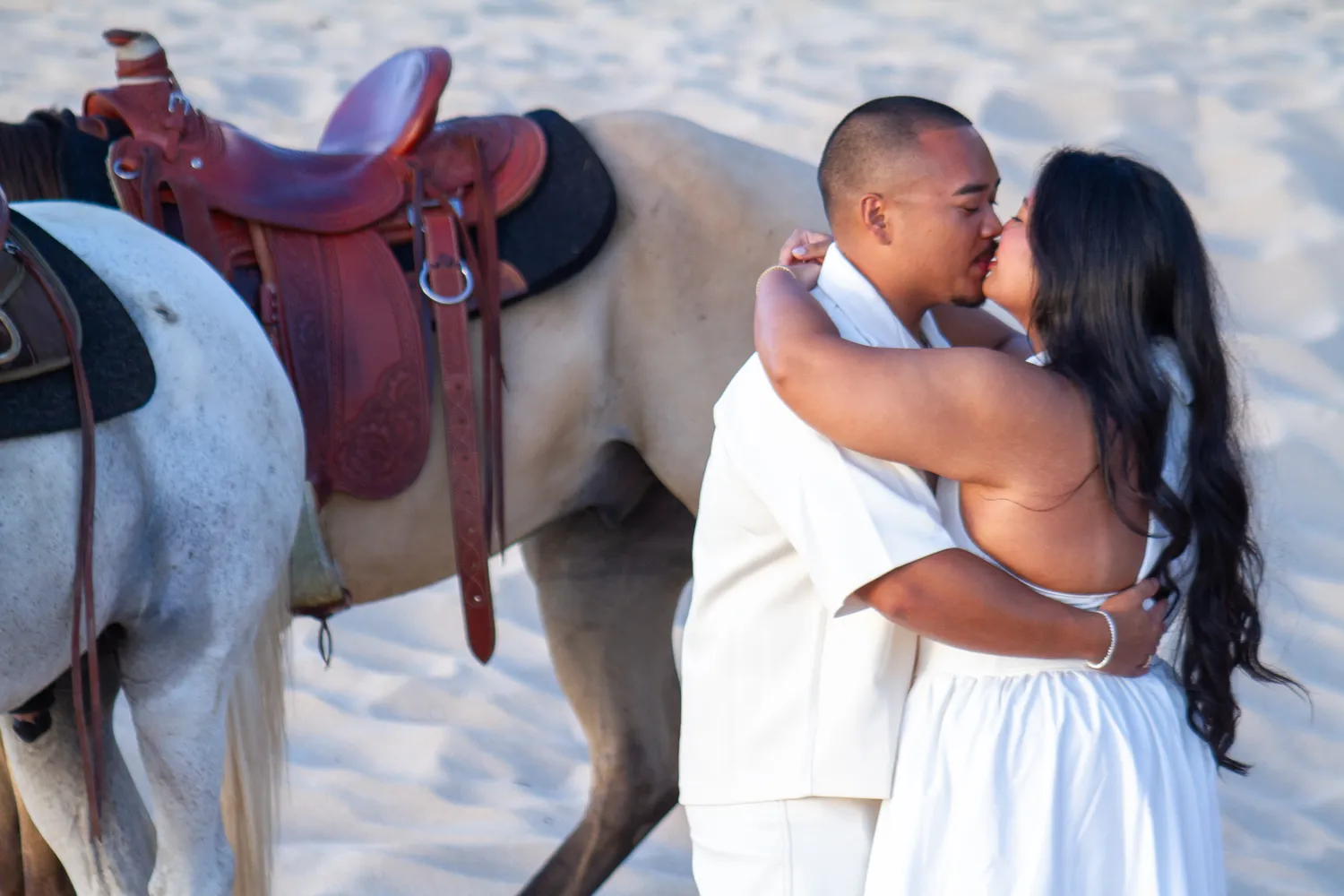 Kiss beside the saddled white horse, at a horseback proposal on Oahu