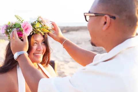 Placing a flower crown on her head, at a horseback proposal on Oahu