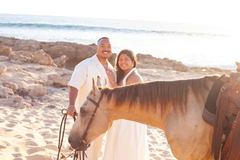 Smiling couple behind the buckskin horse, at a horseback proposal on Oahu