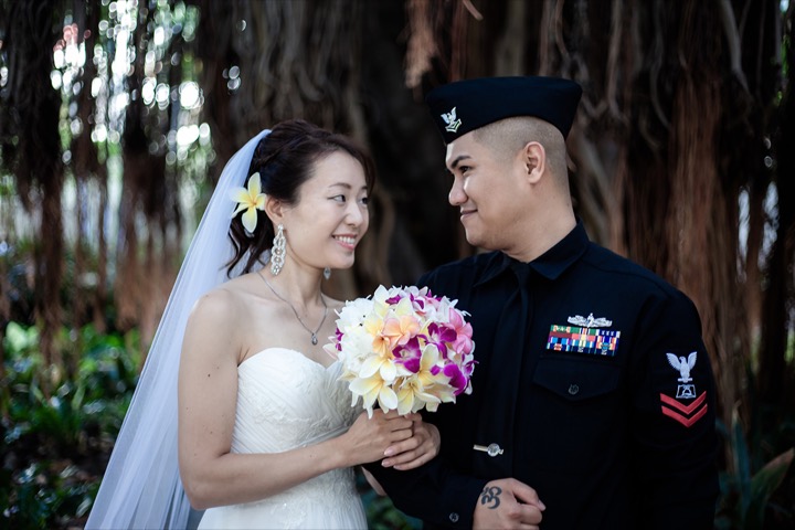 the groom in his sailors outfit looking at the bride in the gardens at the hale koa hotel