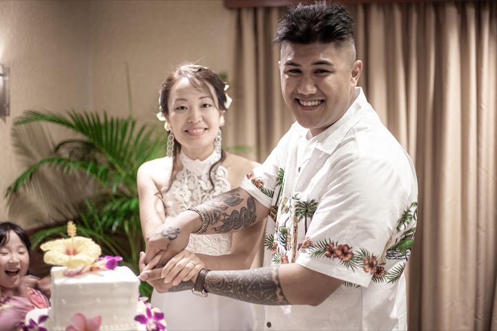 cutting the 3 tier cake with plumeria and orchids on it