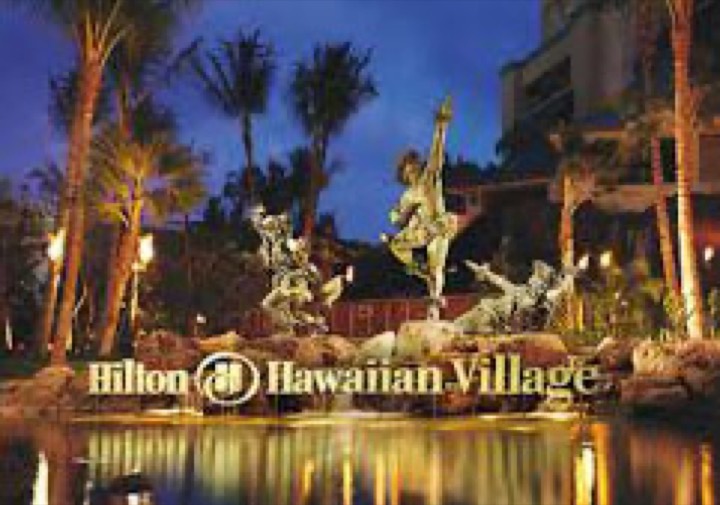 Hilton Hawaiian Village sign and hula dancer statue lit up at night