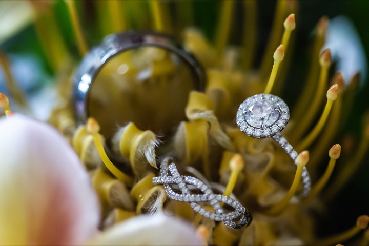 Wedding ring resting in yellow protea and plumeria flowers