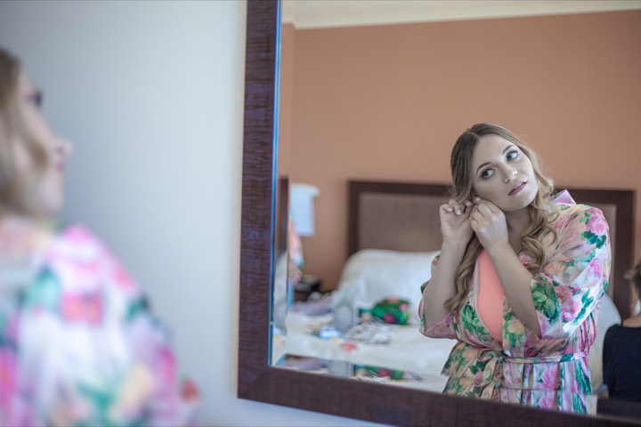 Lauren putting on her earrings in the mirror of her Hilton room