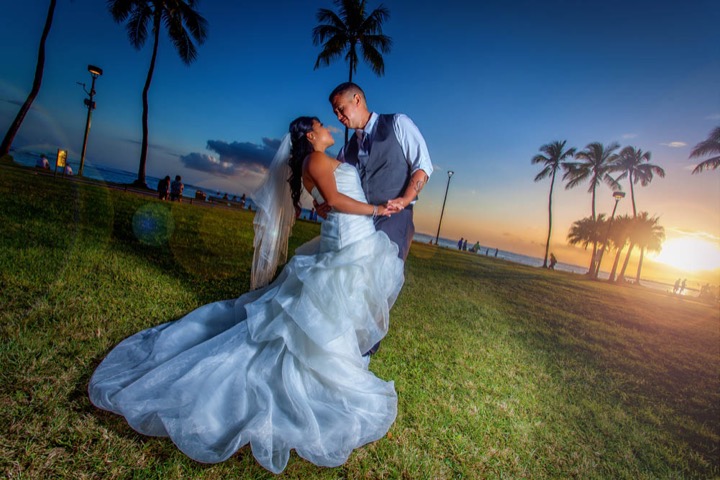 Groom dipping his bride at sunset on the Hale Koa lawn in Waikiki