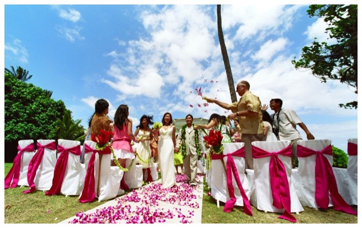 Guests celebrating as the couple walks down a petal aisle at the Kahala Resort