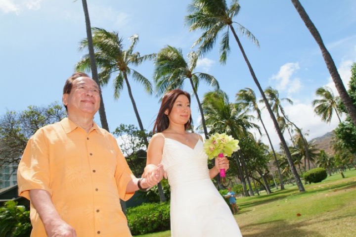 Bride walking down the aisle with her father under the palms at the Kahala Resort