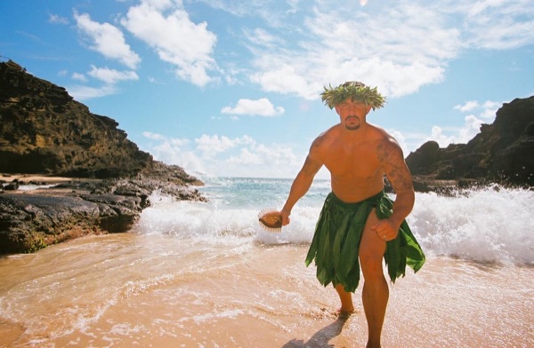 Jamillah and Brandon in grass skirts and haku leis at the cove, up close
