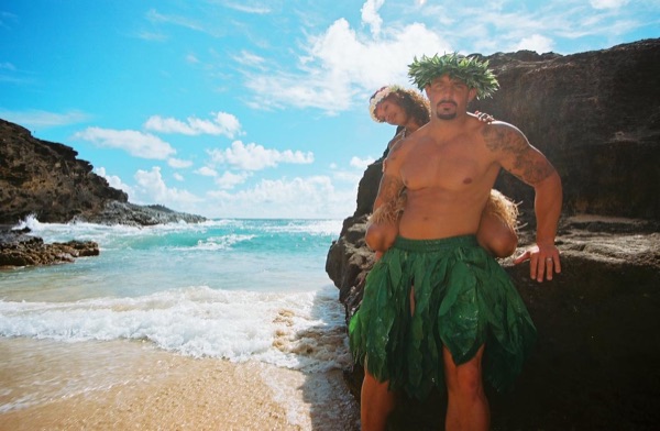 Jamillah and Brandon in grass skirts and haku leis at the cove, from another angle