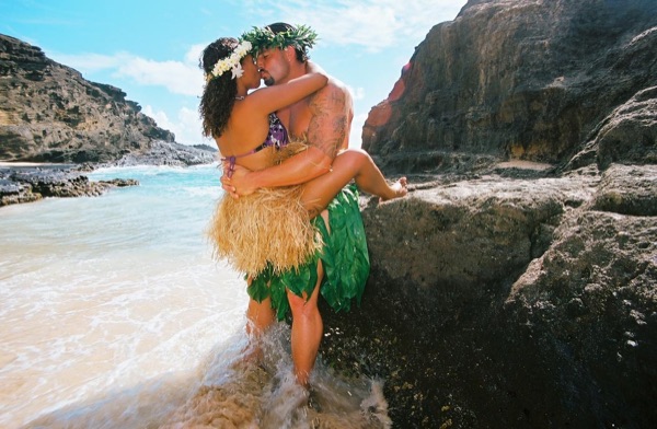Jamillah and Brandon in grass skirts and haku leis at the cove, close up