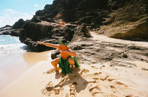 Jamillah and Brandon in grass skirts and haku leis at the cove, arm in arm