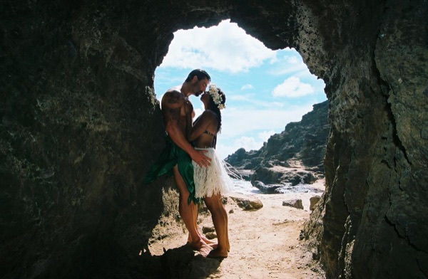 Jamillah and Brandon in a lava tube cave by the beach, wide view