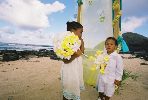 Kids playing with the yellow flower bouquets by the gazebo, under a blue sky