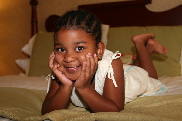 The flower girl lying on the bed with her chin in her hands