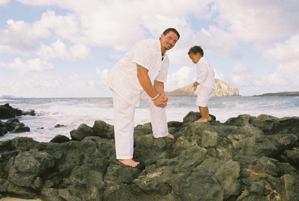 Brandon playing with his son Cameron on the beach, smiling