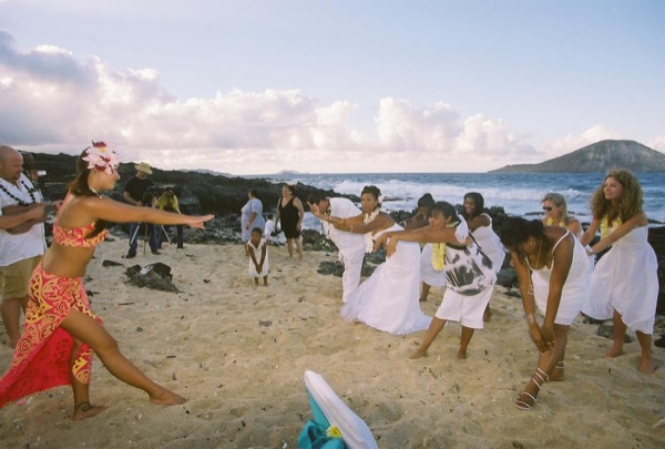 Guests learning the hula with dancer Keveca, under a blue sky