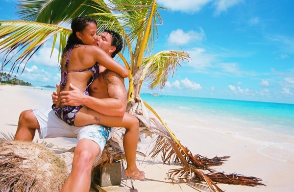 Jamillah and Brandon under a leaning palm at Lanikai, side by side
