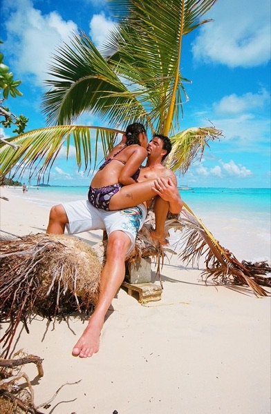 Jamillah and Brandon under a leaning palm at Lanikai, laughing together