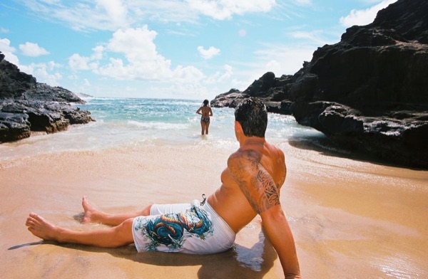 Brandon lying on the sand as the waves wash in at the cove