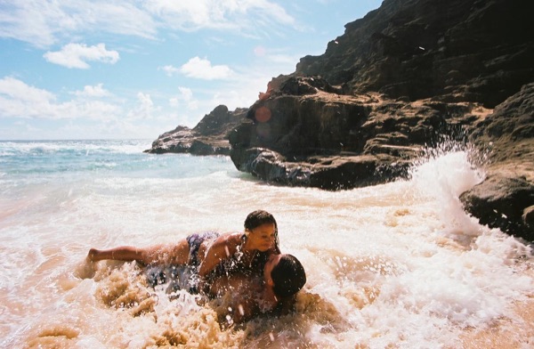 Brandon lying on the sand as the waves wash in at the cove, in the afternoon light