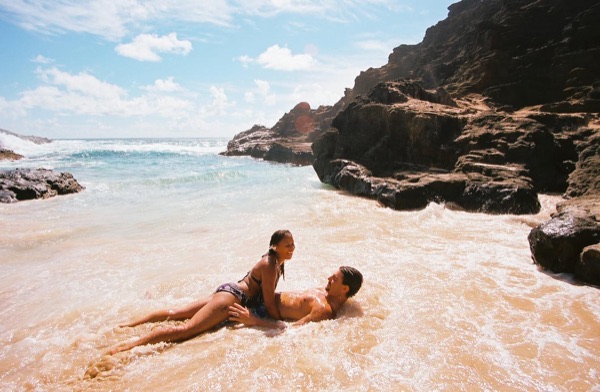 Brandon lying on the sand as the waves wash in at the cove, close together