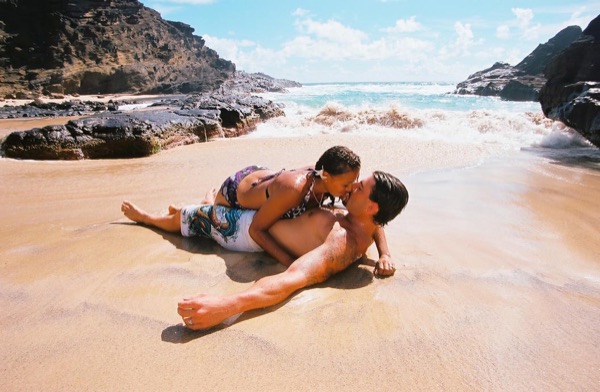 Brandon lying on the sand as the waves wash in at the cove, looking at each other