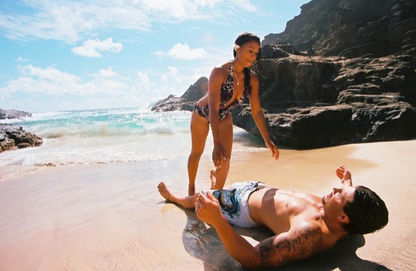 Brandon lying on the sand as the waves wash in at the cove, smiling