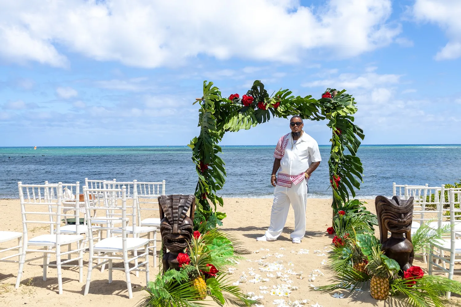 The arch and white chairs on the sand by the ocean