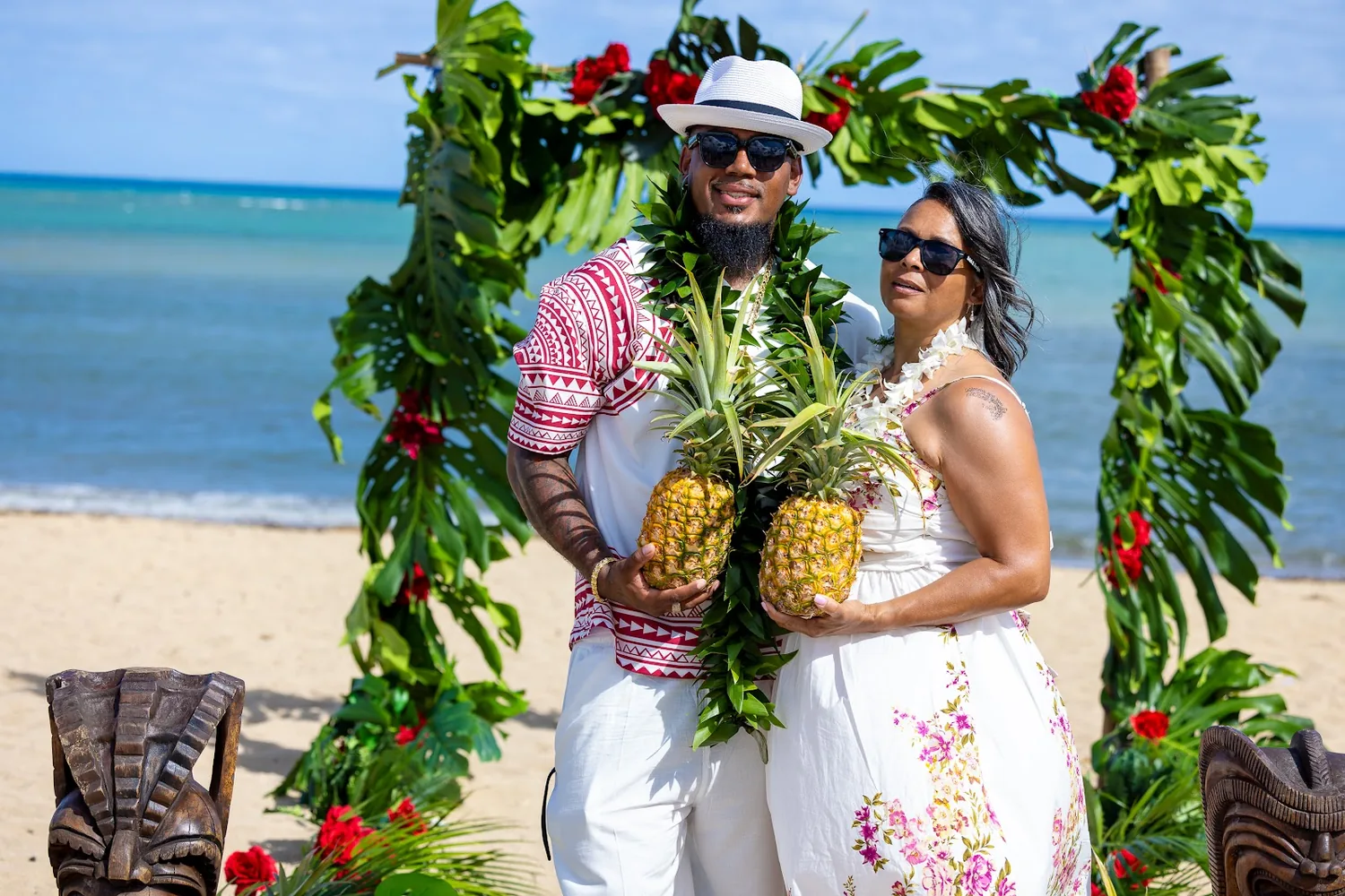 Jocelyn and Erick holding pineapples at the arch
