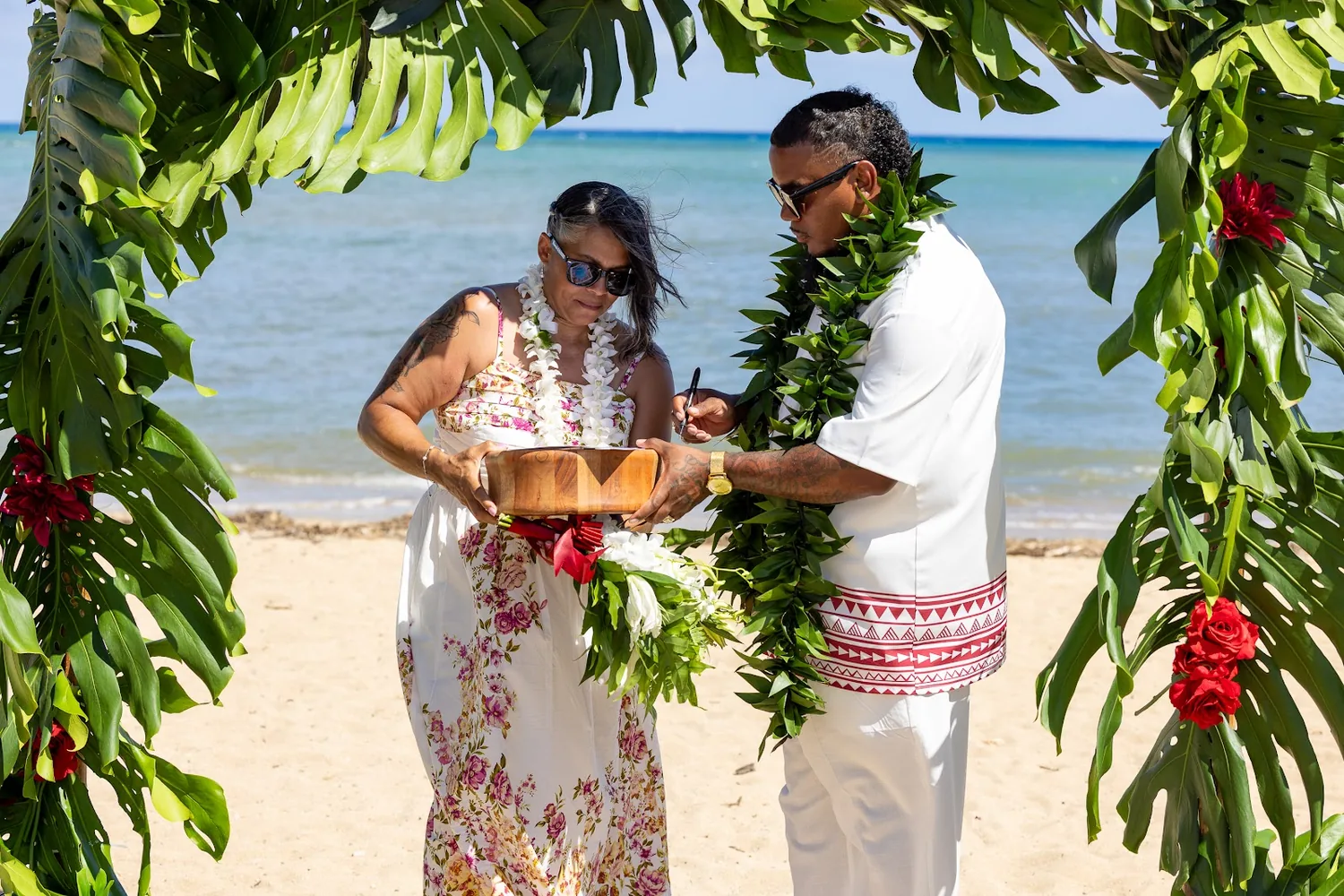 Jocelyn and Erick holding the wooden kava bowl together under the arch