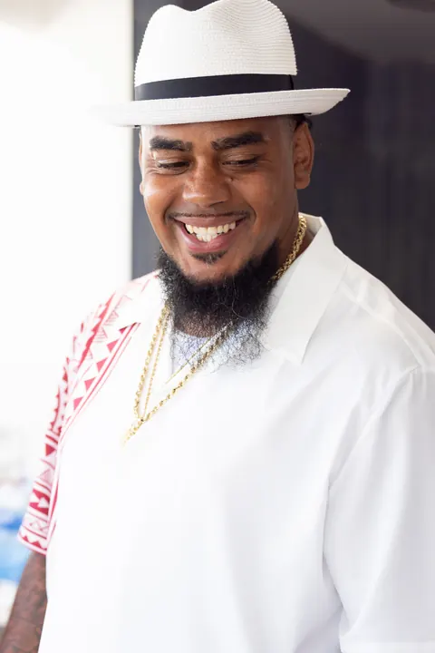 Erick smiling in his white hat and white outfit