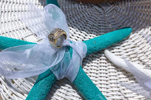 A turquoise starfish ring pillow with white ribbon