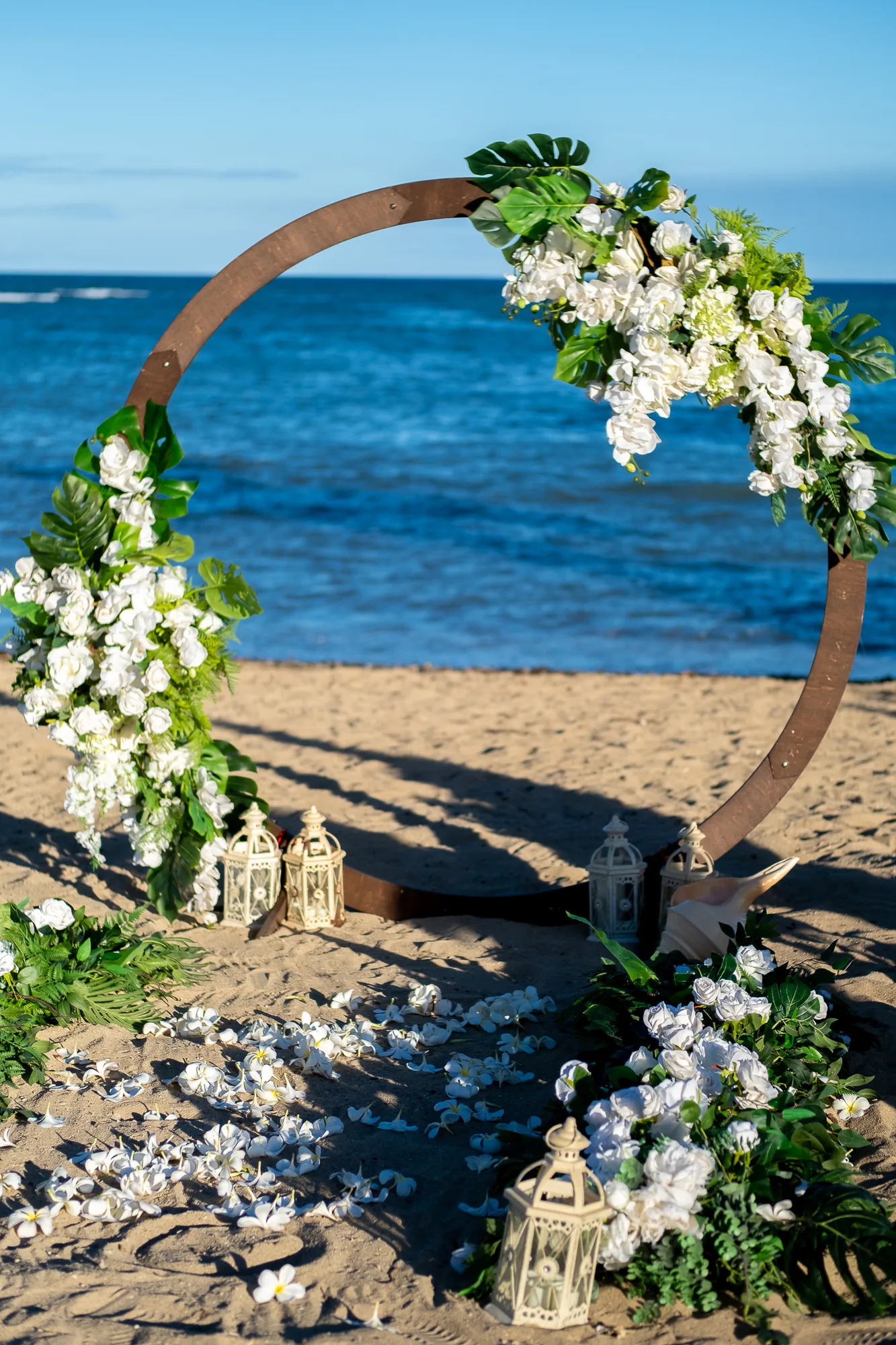 The circle archway dressed with white orchids and monstera leaves by the ocean