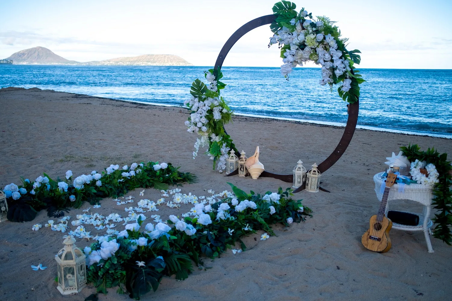 A white plumeria aisle with greenery on both sides leading to the circle archway