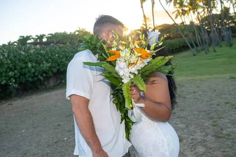 A kiss behind the bouquet by the palm trees