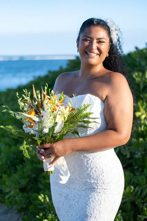 Dianna smiling with her tropical bouquet by the green beach naupaka
