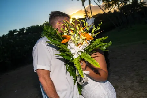 A kiss behind the bouquet at sunset