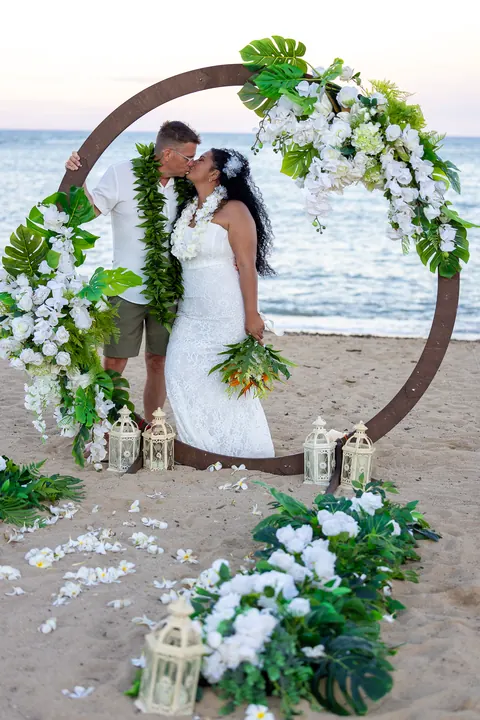 A kiss in the archway with the white flower aisle