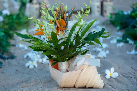 Dianna&rsquo;s tropical bouquet resting by a conch shell on the sand