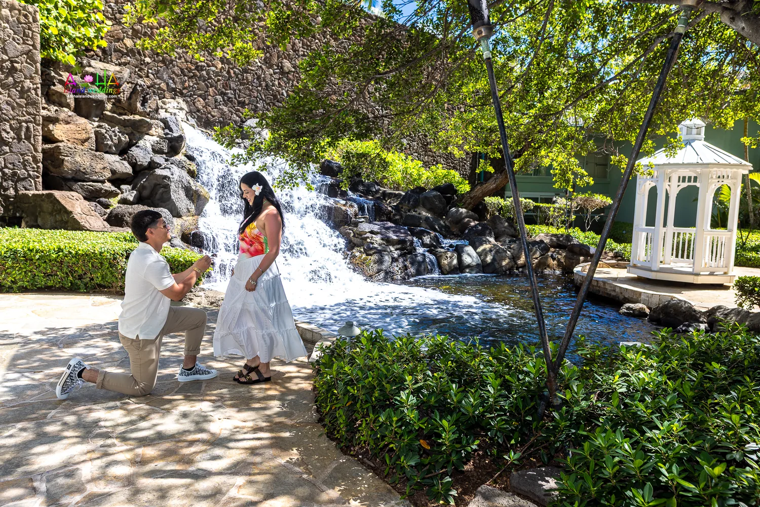 He kneels to propose by the waterfall and gazebo
