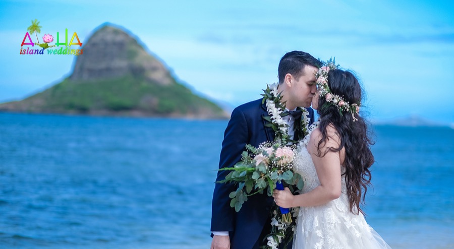 Giselle and her groom kiss in front of Chinaman's Hat after their wedding