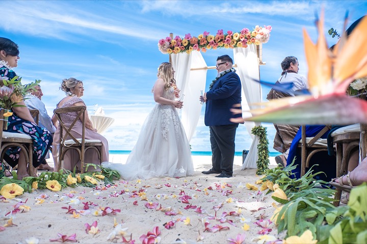 Lauren and Johnathan saying their vows under the flower bamboo arch