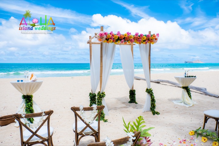 Beach ceremony setup with pink, yellow and orange birds of paradise at Waimanalo