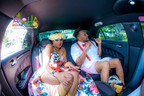 A vow renewal couple in leis riding together in the back of a car on Oahu