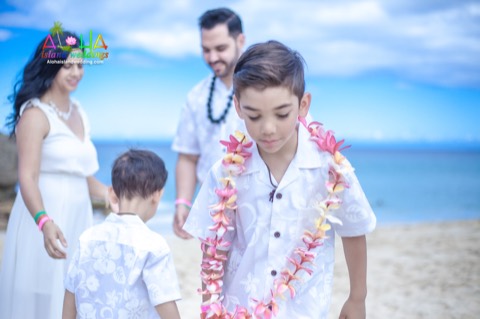 A son in a flower lei walking back after his parents gave it to him at Makua beach