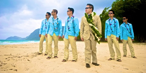 The groom in a maile lei with white orchids beside his groomsmen in Hawaii