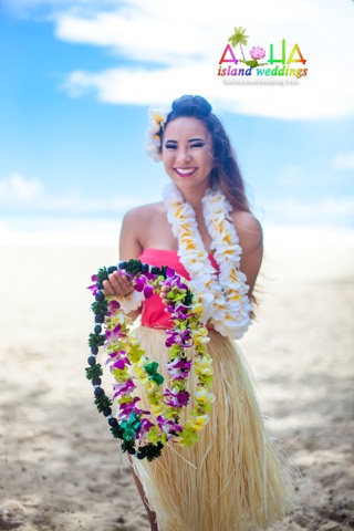A hula dancer in a grass skirt holding colorful flower leis on Oahu