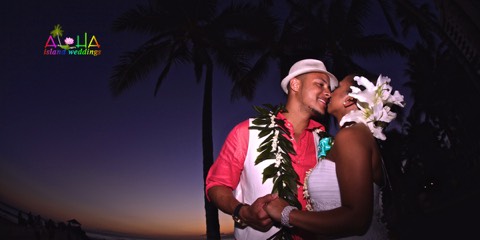 A couple in flower leis embracing under the palm trees at night in Hawaii