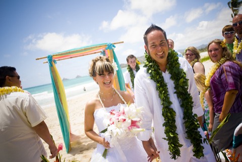 Becky and Eric in maile leis on the beach after their estate wedding on Oahu