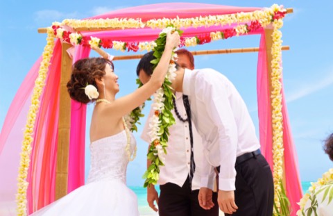 Rei places a maile lei on her groom during their lei exchange in Hawaii